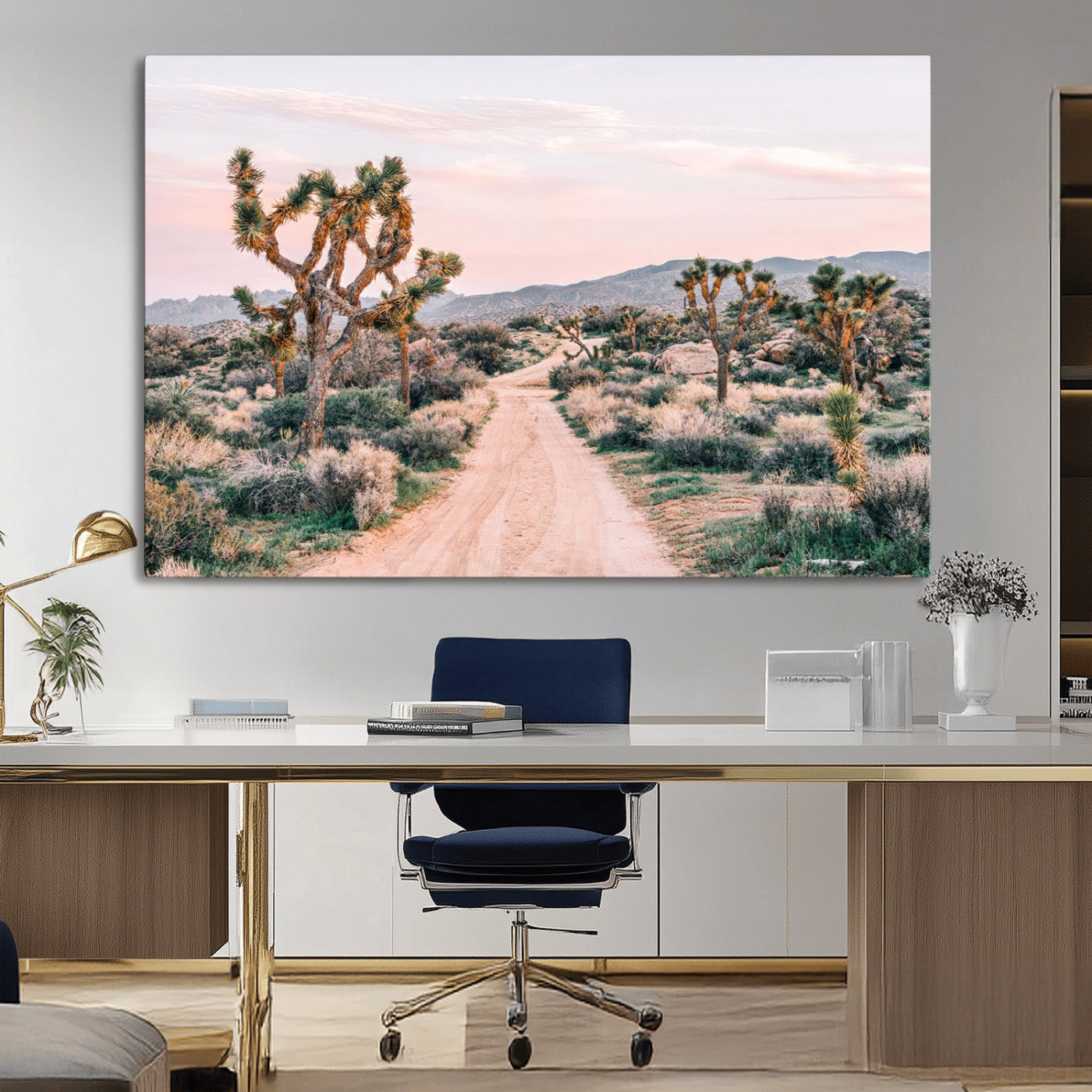 A dusty road winding through Joshua Tree National Park, framed by iconic twisted trees and warm desert tones under a soft pastel sky.