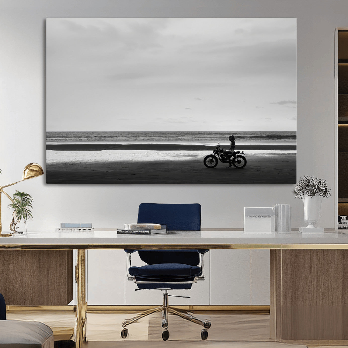 A motorcyclist on a vast beach, gazing at the ocean, capturing a moody and tranquil coastal adventure in black and white.