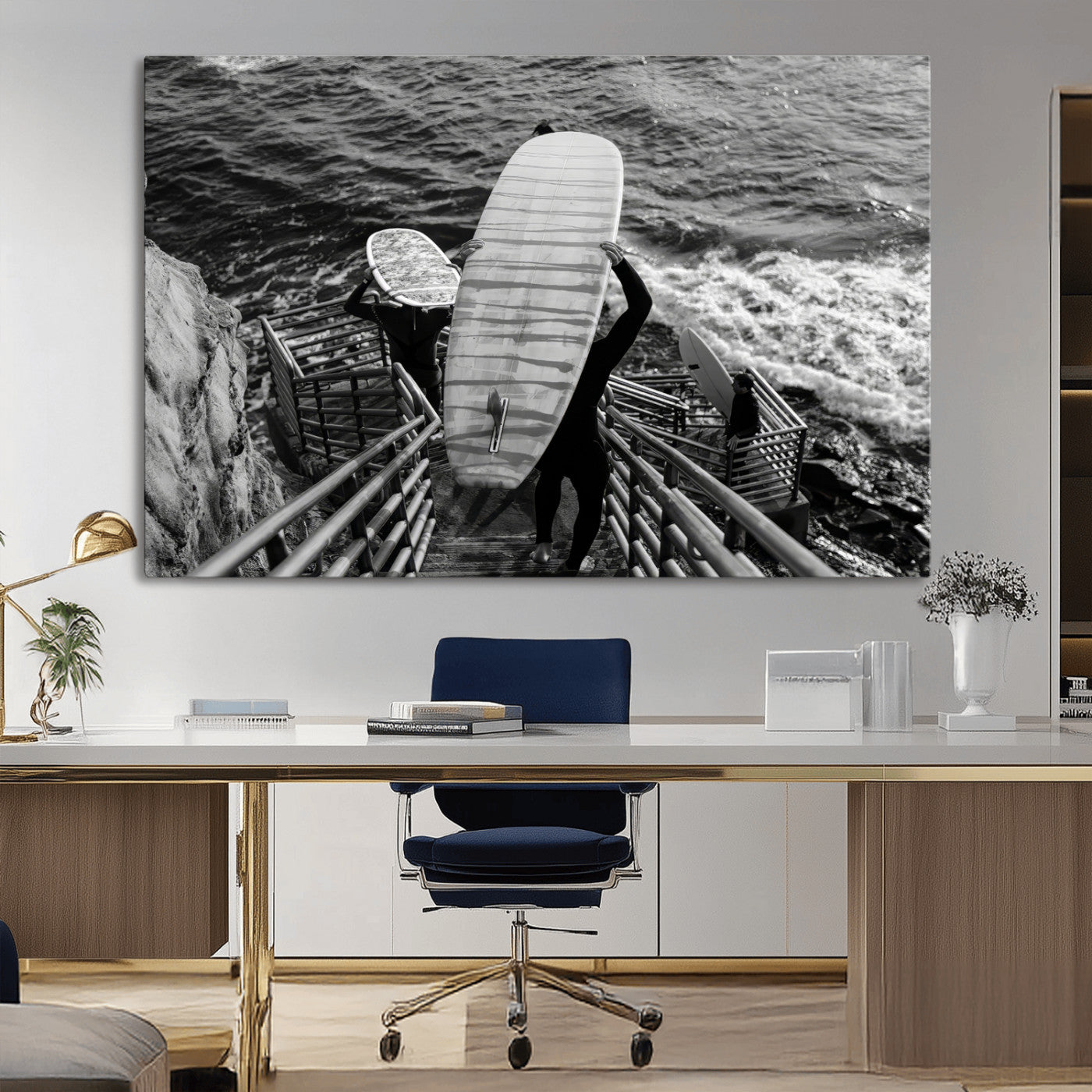 Black and white photo of surfers carrying boards down a rugged cliffside stairway, capturing a bold and adventurous coastal scene.