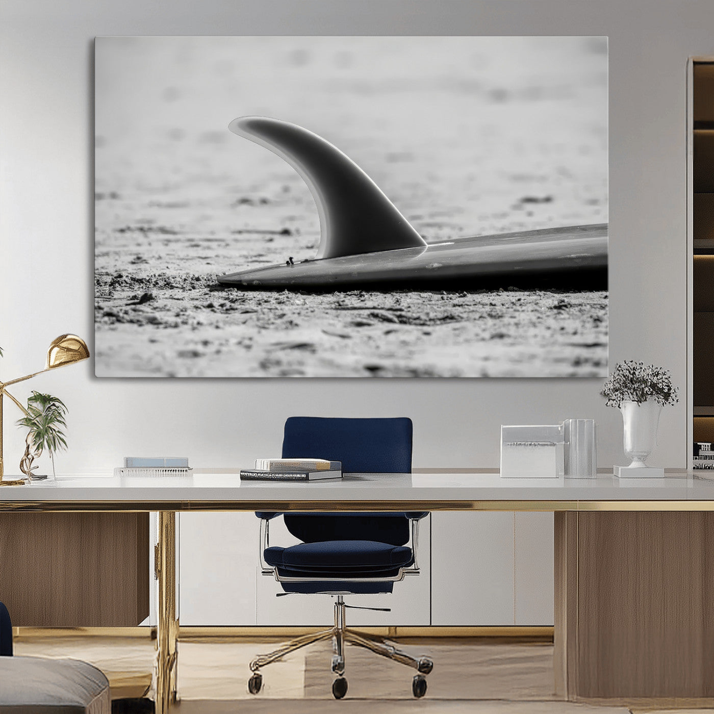 A black and white close-up of a surfboard fin resting on the sandy shore, highlighting minimalist beach aesthetics and classic surf culture.