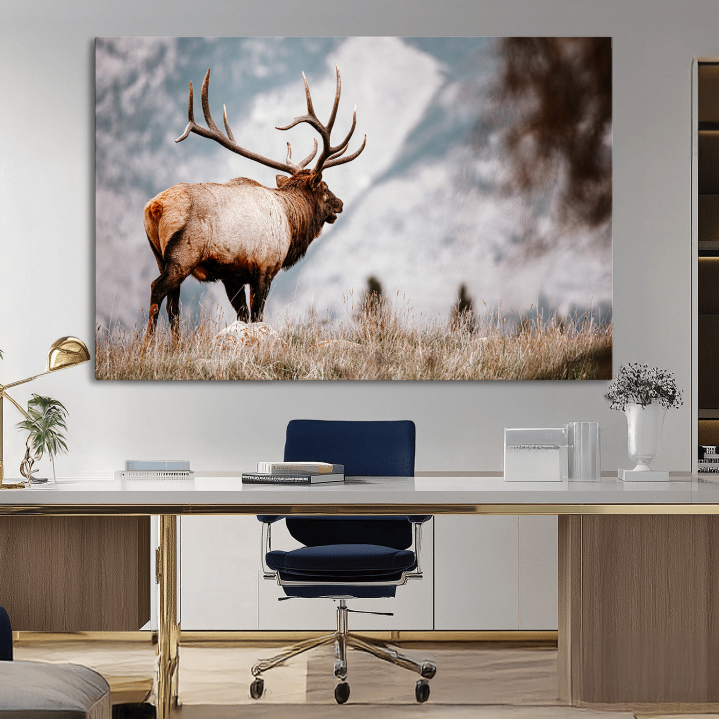 Majestic elk with large antlers standing in grass with snowy mountains in background, perfect for rustic cabin or lodge style decor.