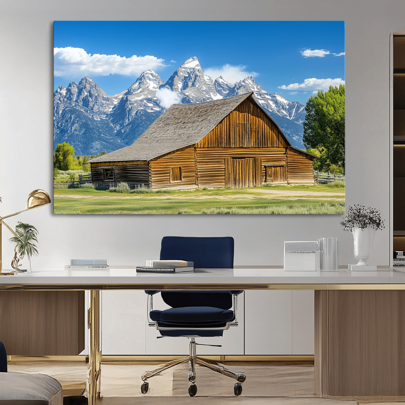 A rustic wooden barn sits in front of towering mountain peaks under a clear blue sky, perfect for farmhouse or cabin style interiors.