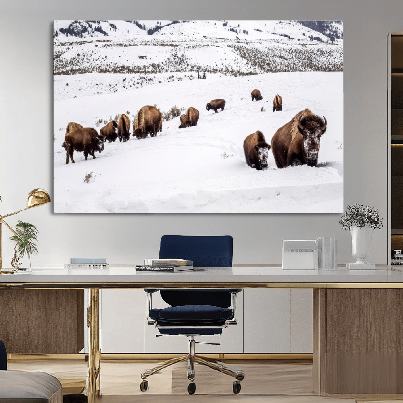 A herd of bison walking through deep snow in a mountain valley, perfect for rustic, cabin or western-themed wall decor.