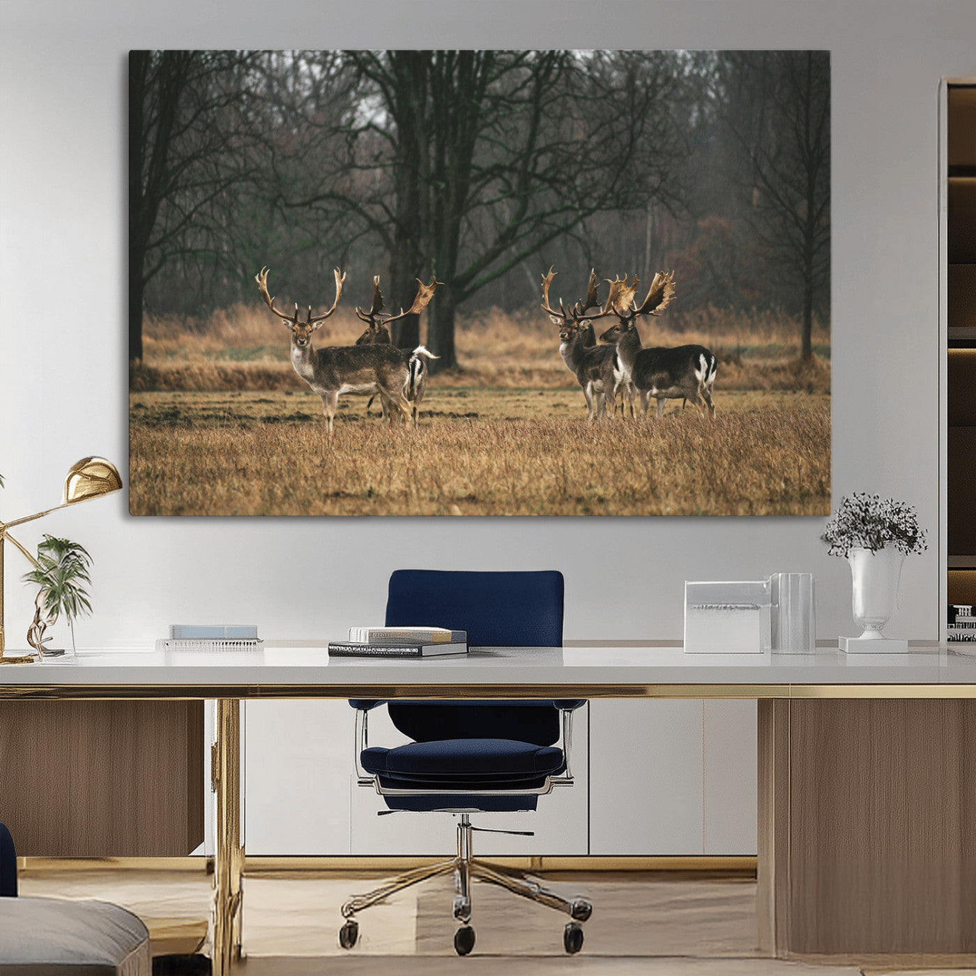 A group of majestic deer standing in a golden field with bare trees in the background, creating a peaceful woodland scene.