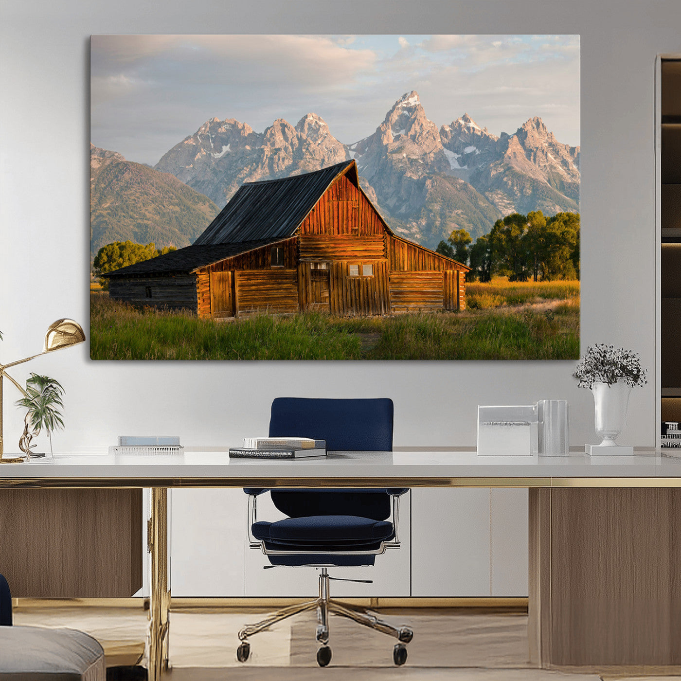 Rustic wooden barn set against towering mountain peaks under warm golden light, creating a peaceful Western countryside scene.