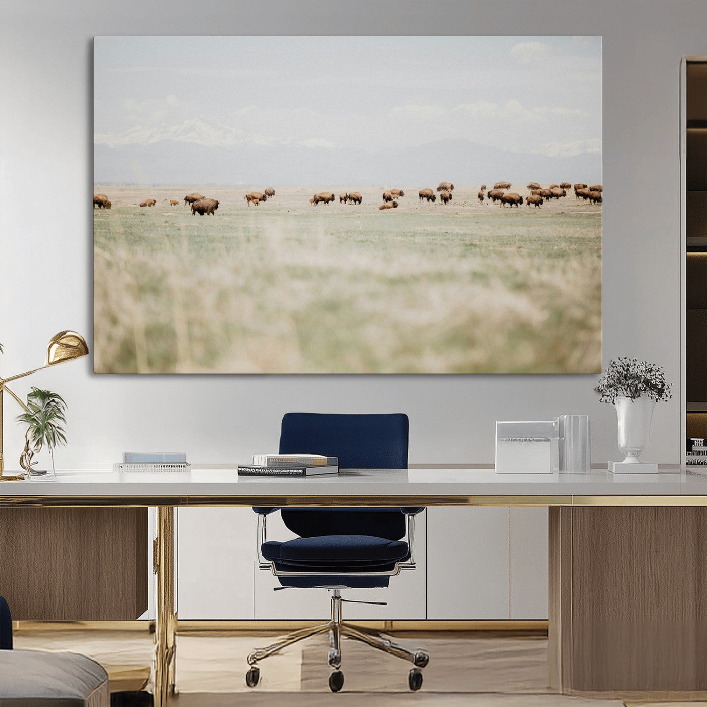 A herd of bison grazing in an open prairie with distant mountains under a soft sky, creating a serene and rustic Western landscape.