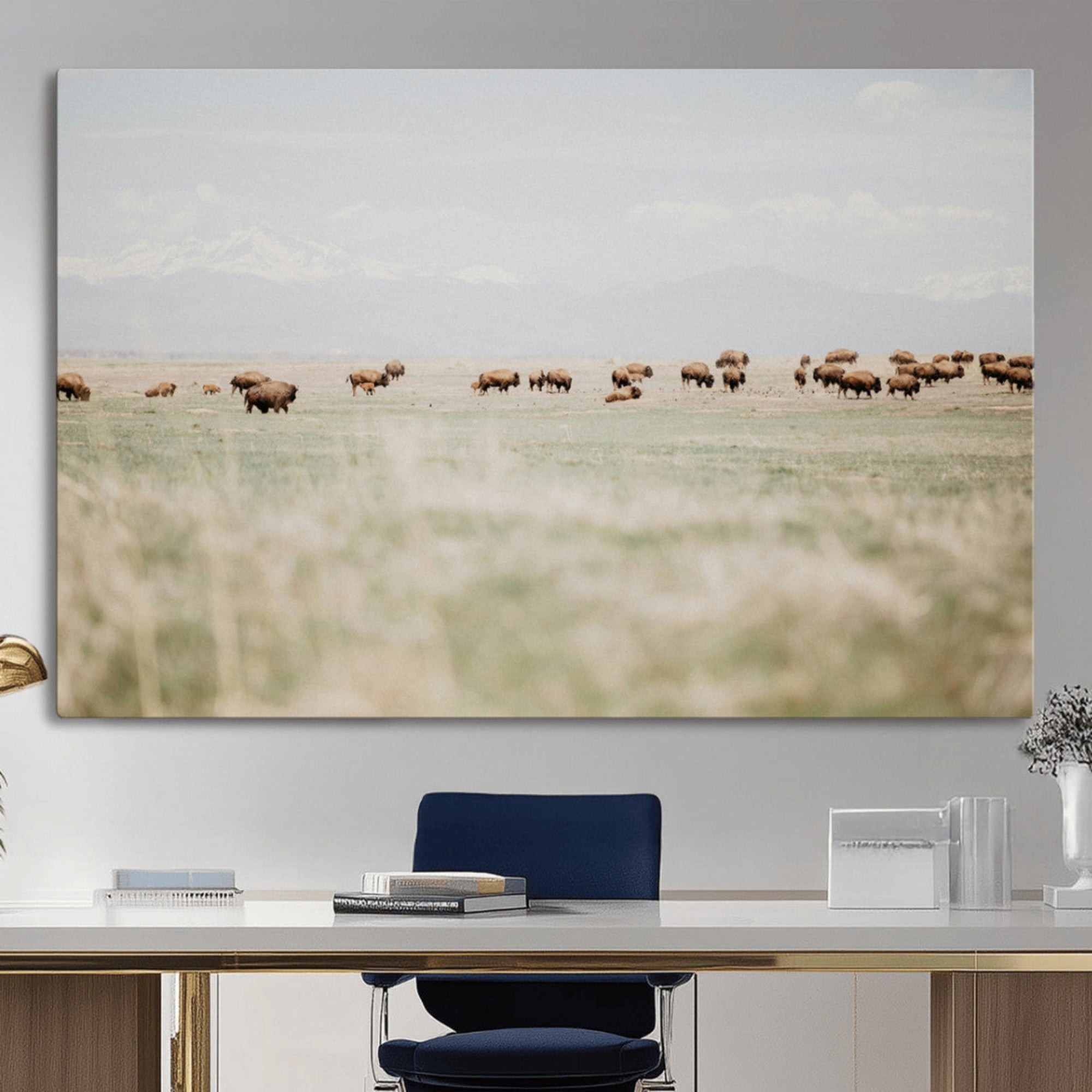 A herd of bison grazing in an open prairie with distant mountains under a soft sky, creating a serene and rustic Western landscape.