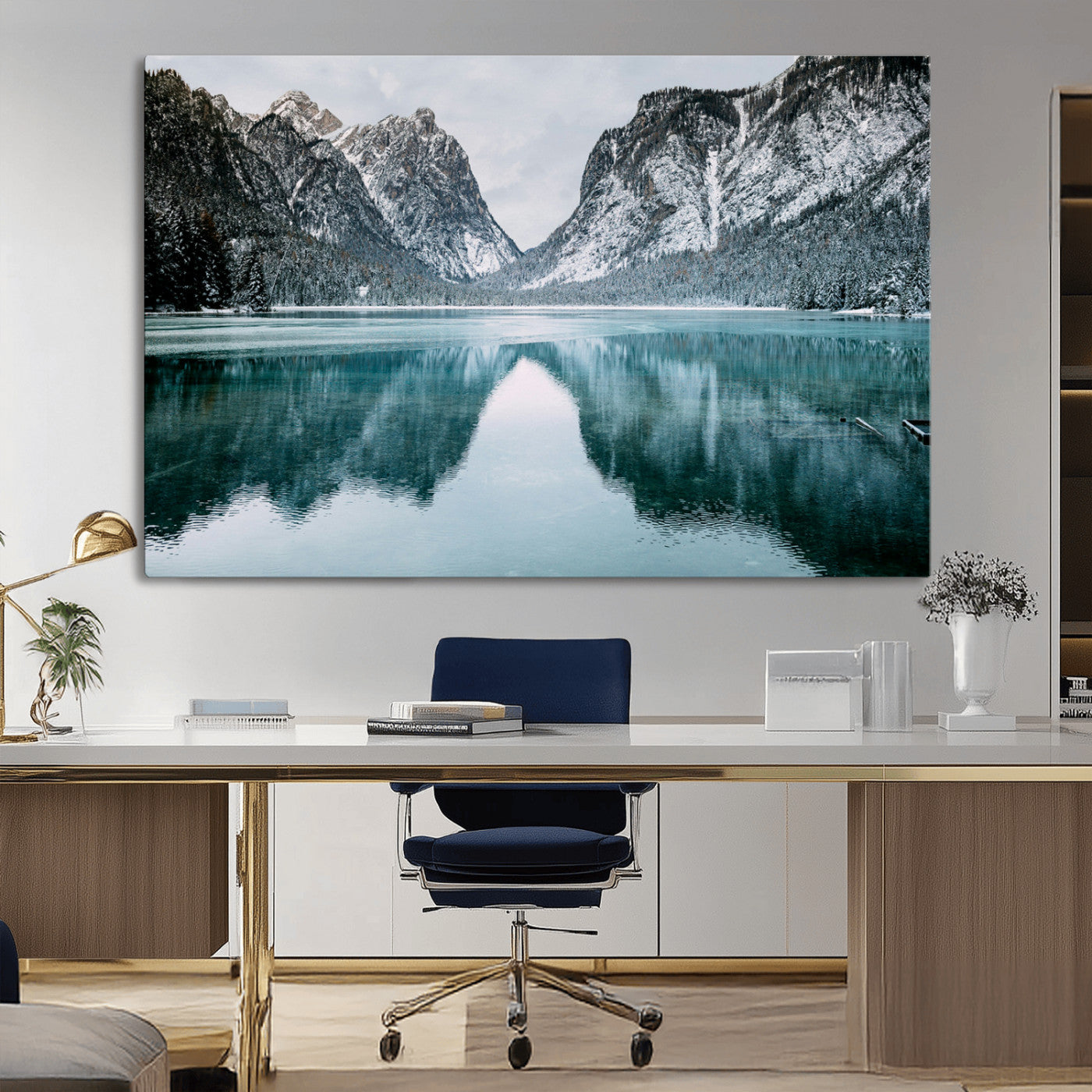 Crystal-clear alpine lake reflecting snow-covered mountains, surrounded by evergreen trees, creating a serene and tranquil winter landscape.