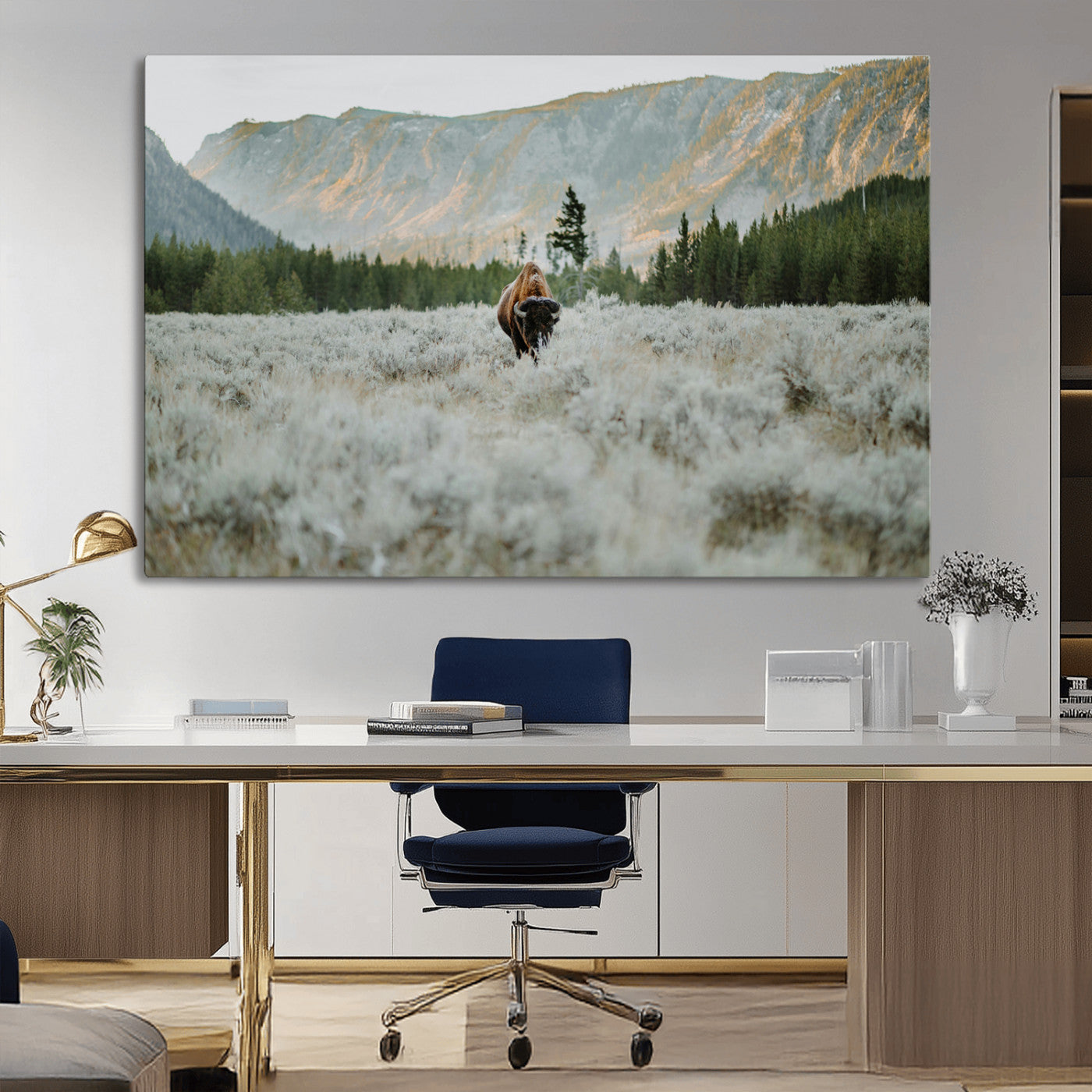 Lone bison standing in a frosted sagebrush field with a pine forest and rugged mountain range in the background under soft morning light – Wall Art Canvas Print.