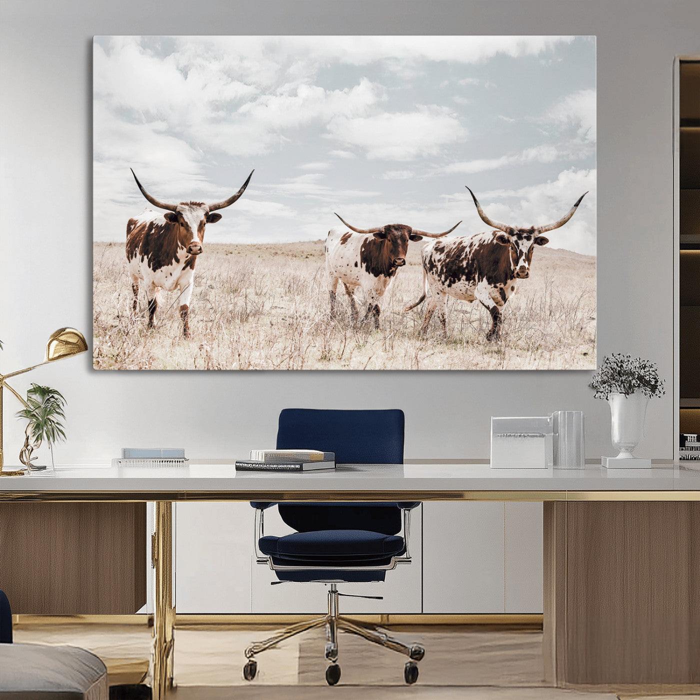 Three Texas Longhorn cattle walking through a dry grassy field under a partly cloudy sky.