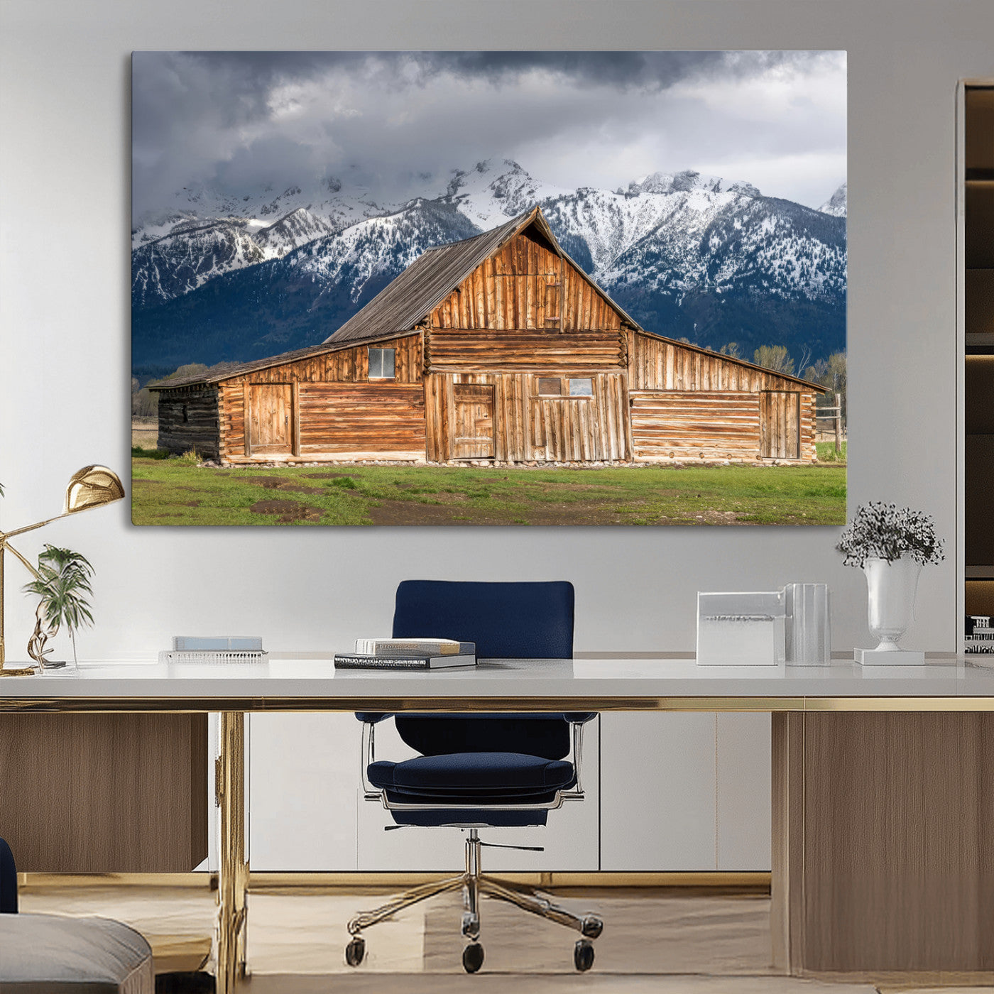 A stunning wall art canvas print featuring a rustic wooden barn set against a backdrop of snow-capped mountains under a dramatic cloudy sky, perfect for adding a touch of rural charm to any space.