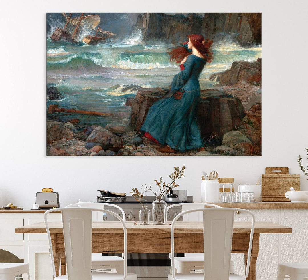 The Miranda by the Shore Wall Art Canvas Print depicts a woman in a blue dress standing by the sea, watching a shipwreck.