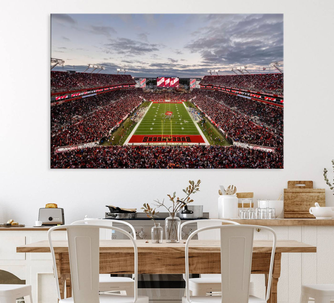 The wall art captures a stunning scene of Raymond James Stadium bathed in the warm hues of sunset. The sky, filled with clouds, provides a dramatic contrast to the vibrant lighting on the field, encapsulating the dynamic energy of a football game.