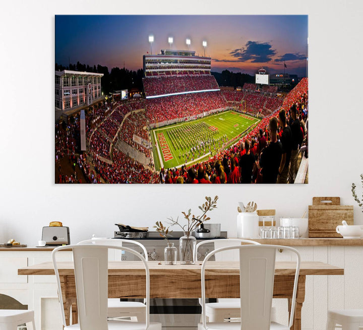 A print of a bustling Carter-Finley Stadium at dusk, featuring fans and a band, captures the essence of NC State Wolfpack football.