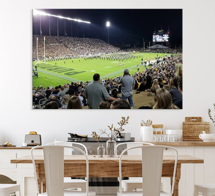 A painting depicting the Purdue Boilermakers football game at Ross-Ade Stadium is illuminated under gallery-quality lights.