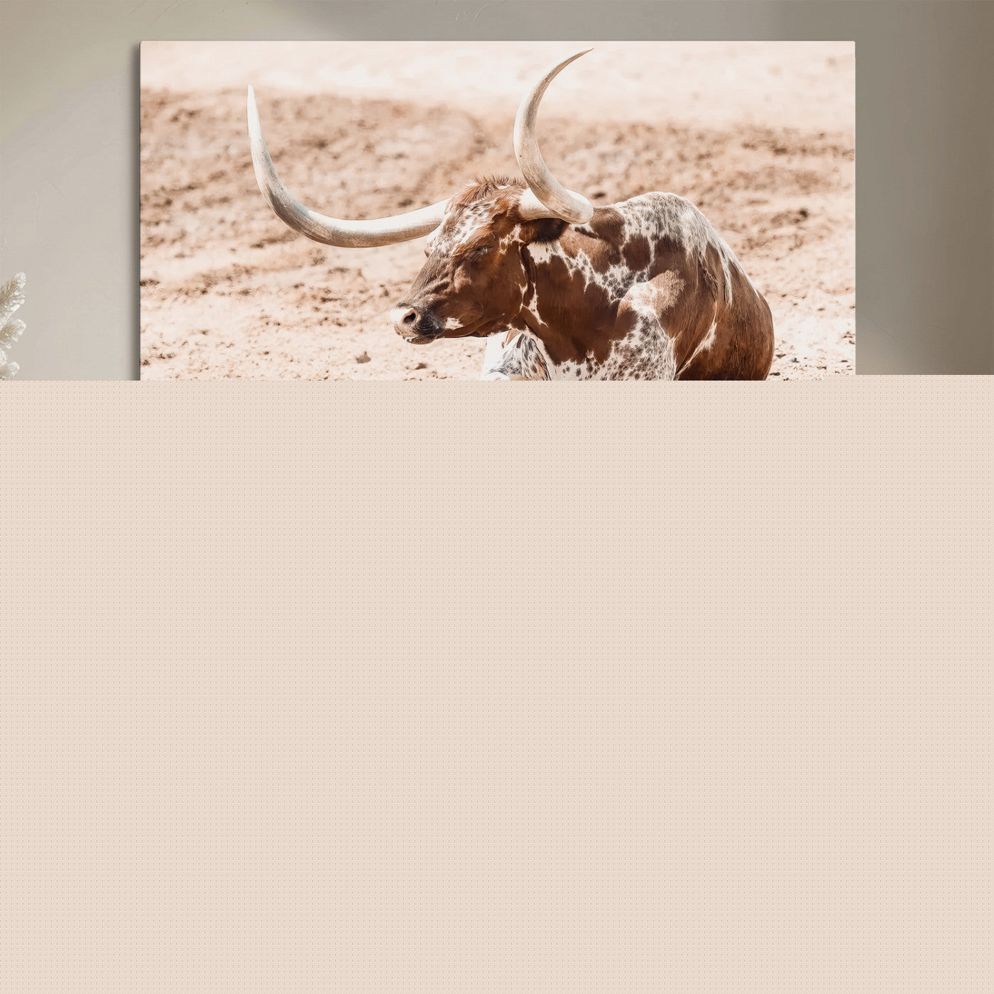 Texas Longhorn bull resting on dusty ground with warm tones, ideal for rustic western or farmhouse-themed wall decor.