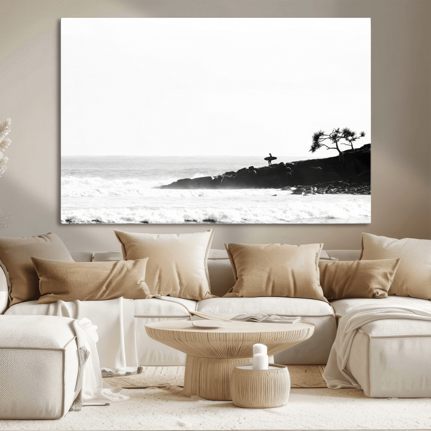 Black and white photo of a surfer standing on rocky cliffs, gazing at the waves, embodying the spirit of adventure and solitude.