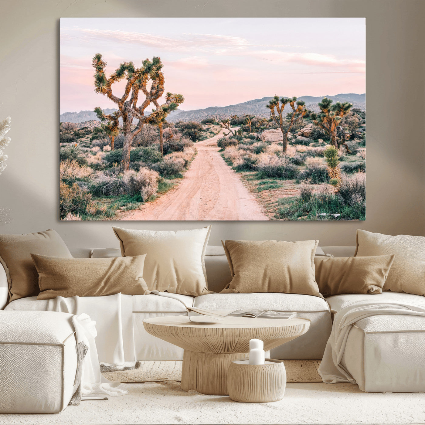 A dusty road winding through Joshua Tree National Park, framed by iconic twisted trees and warm desert tones under a soft pastel sky.