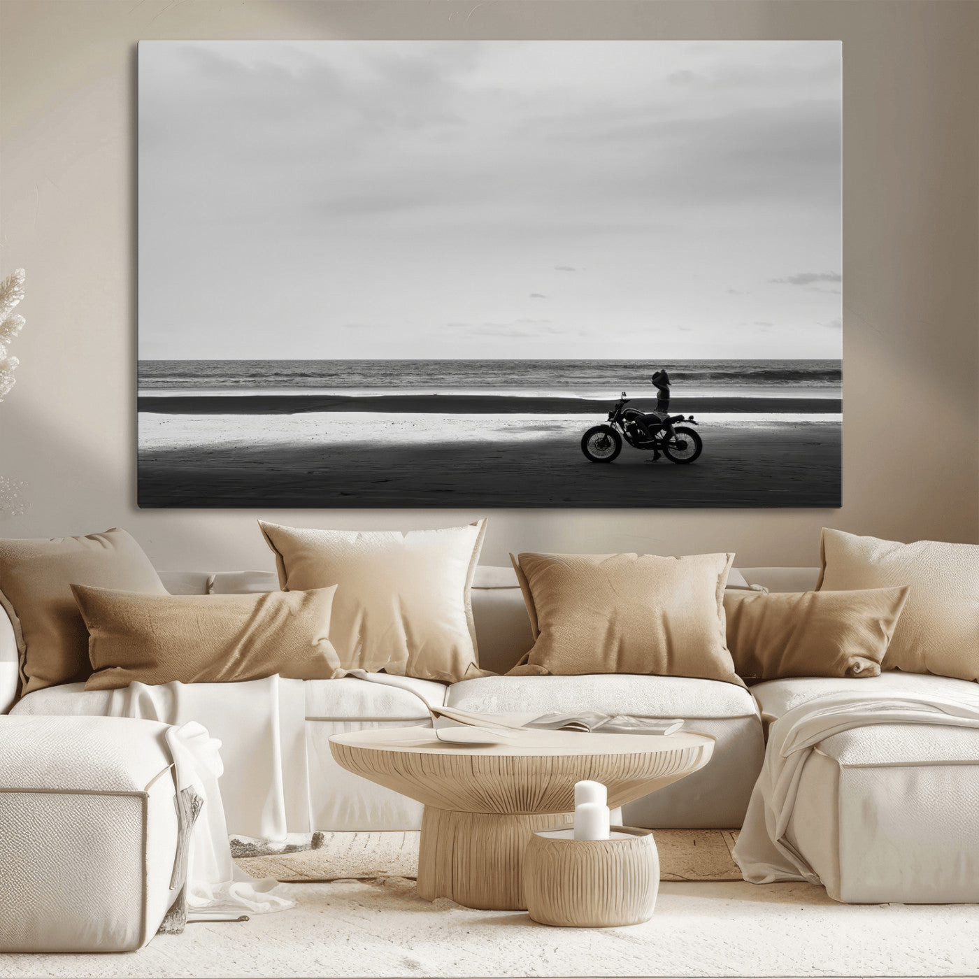A motorcyclist on a vast beach, gazing at the ocean, capturing a moody and tranquil coastal adventure in black and white.