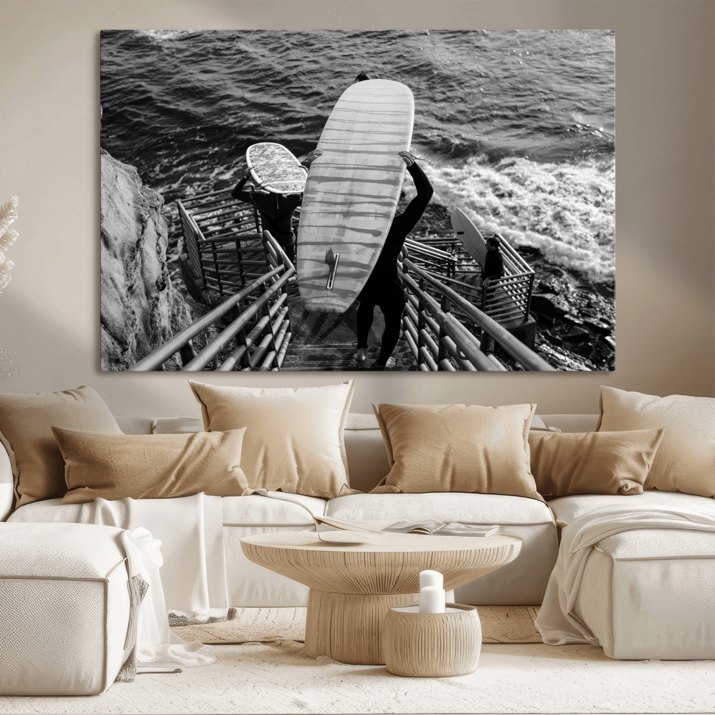 Black and white photo of surfers carrying boards down a rugged cliffside stairway, capturing a bold and adventurous coastal scene.