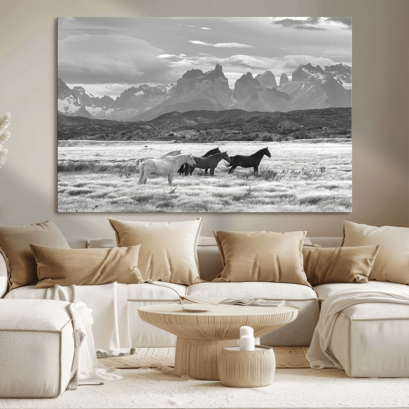 A black and white landscape of wild horses grazing in a vast grassland with towering mountains in the background, creating a moody and rustic western aesthetic.