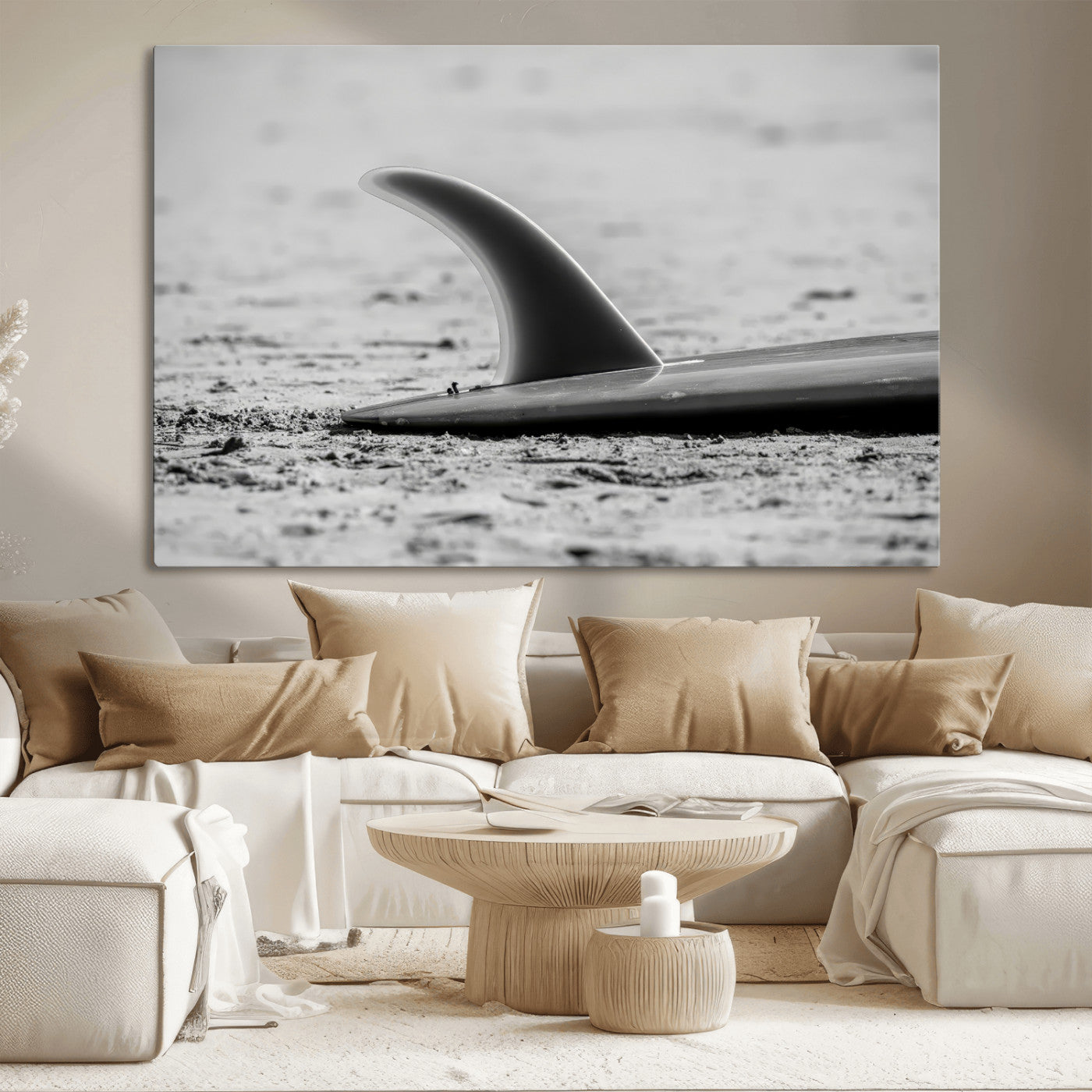 A black and white close-up of a surfboard fin resting on the sandy shore, highlighting minimalist beach aesthetics and classic surf culture.