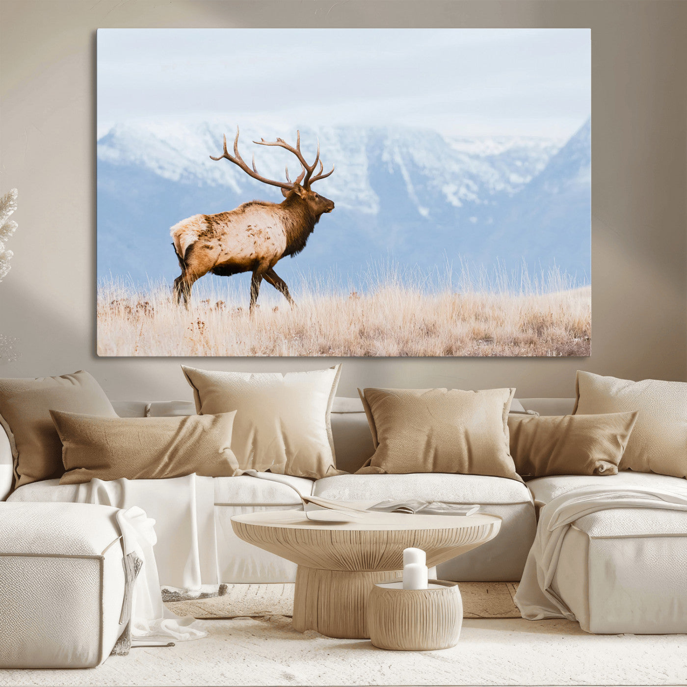 An elk walking on snowy grassland with majestic mountains in the background, ideal for rustic lodge or cabin wall decor.