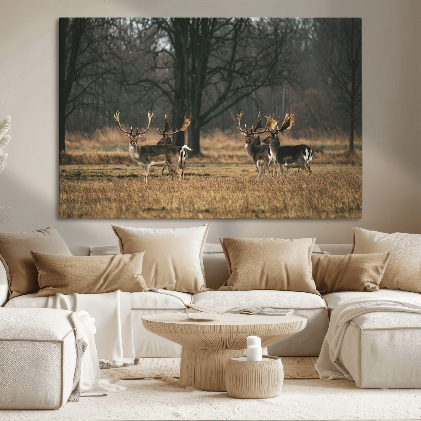 A group of majestic deer standing in a golden field with bare trees in the background, creating a peaceful woodland scene.