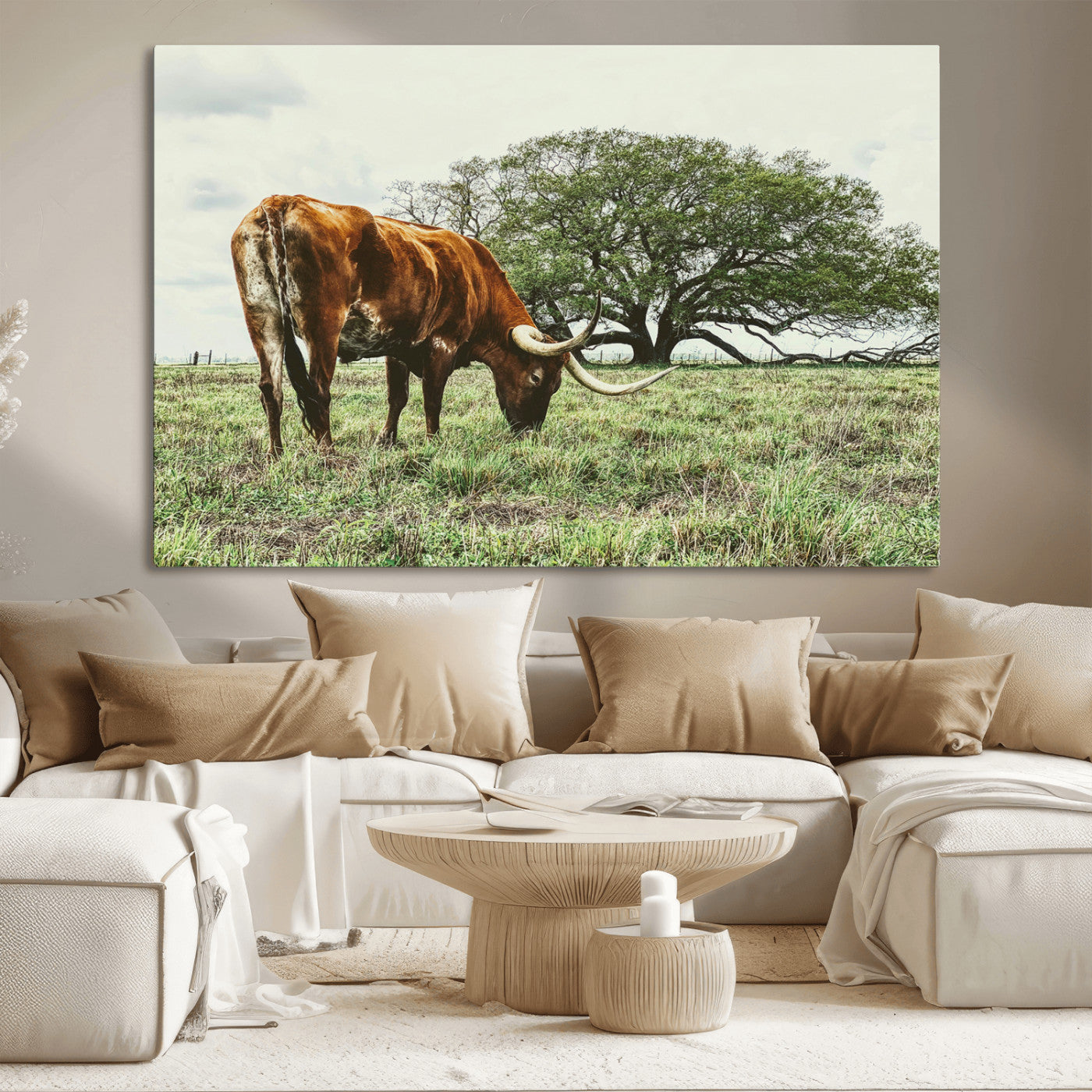 A Texas Longhorn grazing in a green pasture with a large tree in the background, evoking a rustic Western and farmhouse aesthetic.