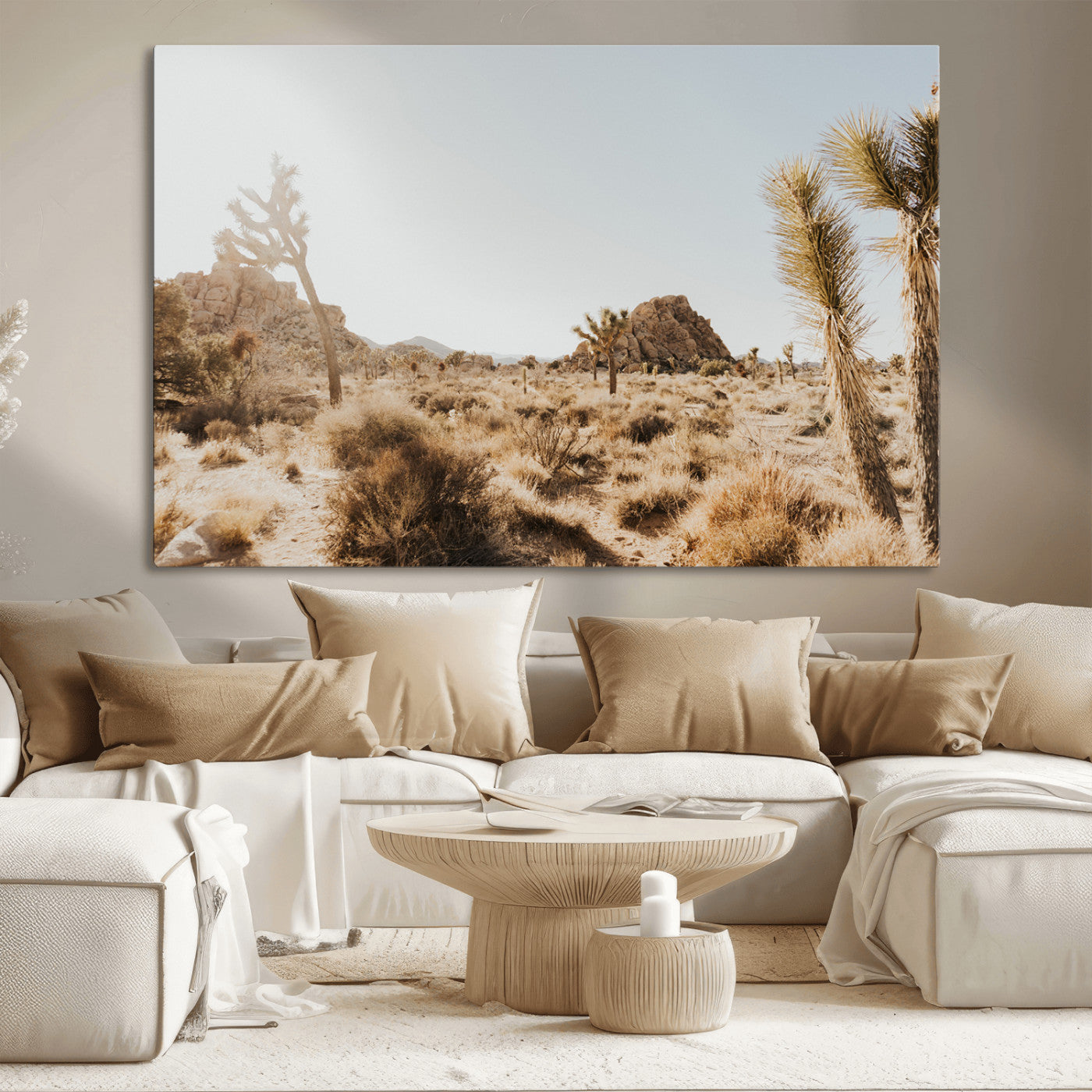 Sunlit desert landscape featuring Joshua trees, rocky formations, and dry bushes under a clear sky.