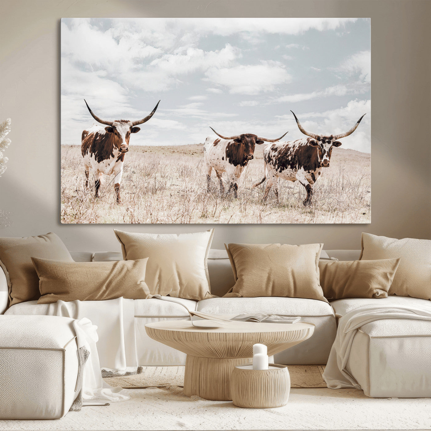 Three Texas Longhorn cattle walking through a dry grassy field under a partly cloudy sky.