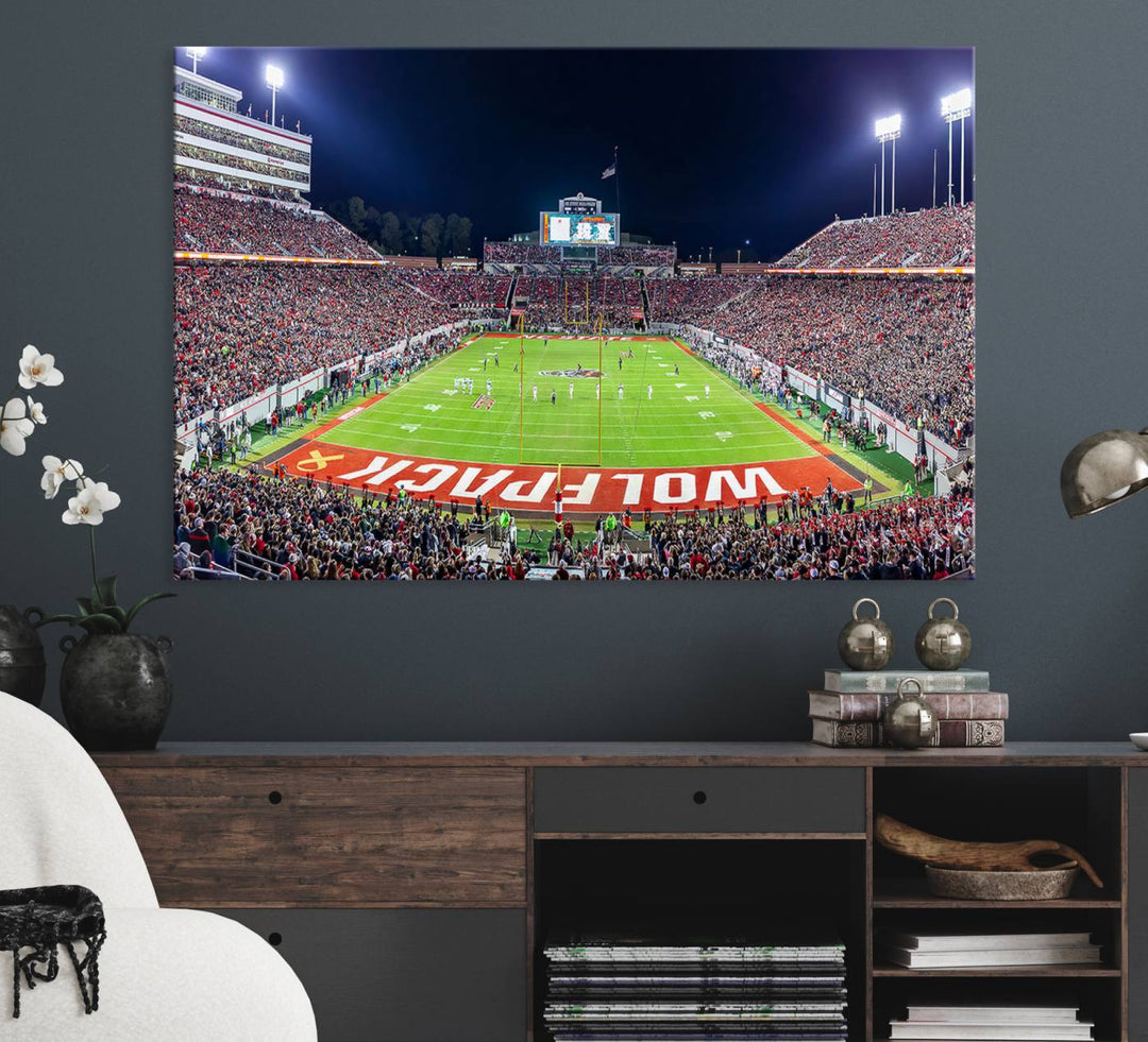 A NC State Wolfpack Football Team print of Carter-Finley Stadium at night features WOLFPACK illuminated brightly in the end zone grass.