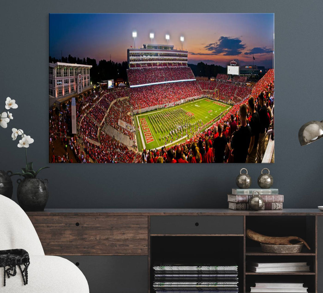 A print of a bustling Carter-Finley Stadium at dusk, featuring fans and a band, captures the essence of NC State Wolfpack football.