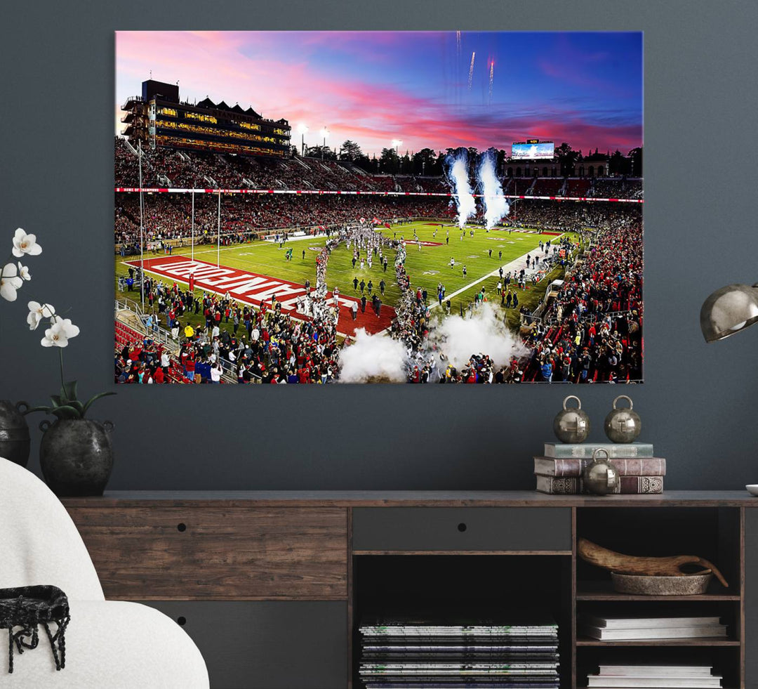 The wall art features a canvas print of the Stanford Cardinal football team, capturing players, fireworks, and smoke against the backdrop of a sunset at Stanford Stadium.