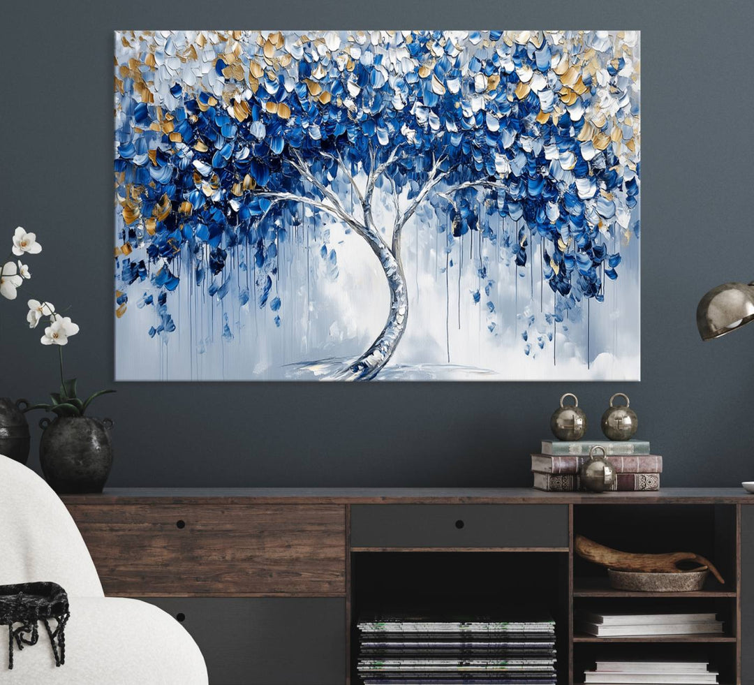 The Blue and Gold Abstract Tree Wall Art showcases a swirl trunk and features blue, silver, and gold leaves on a framed canvas print.