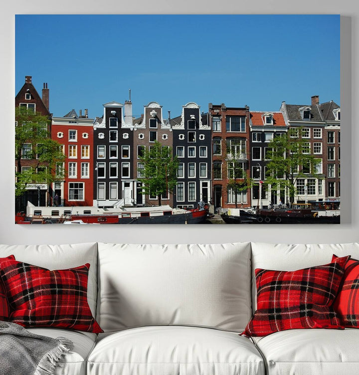 The Amsterdam City Wall Art Canvas Print showcases colorful traditional canal houses and boats set against a clear blue sky.