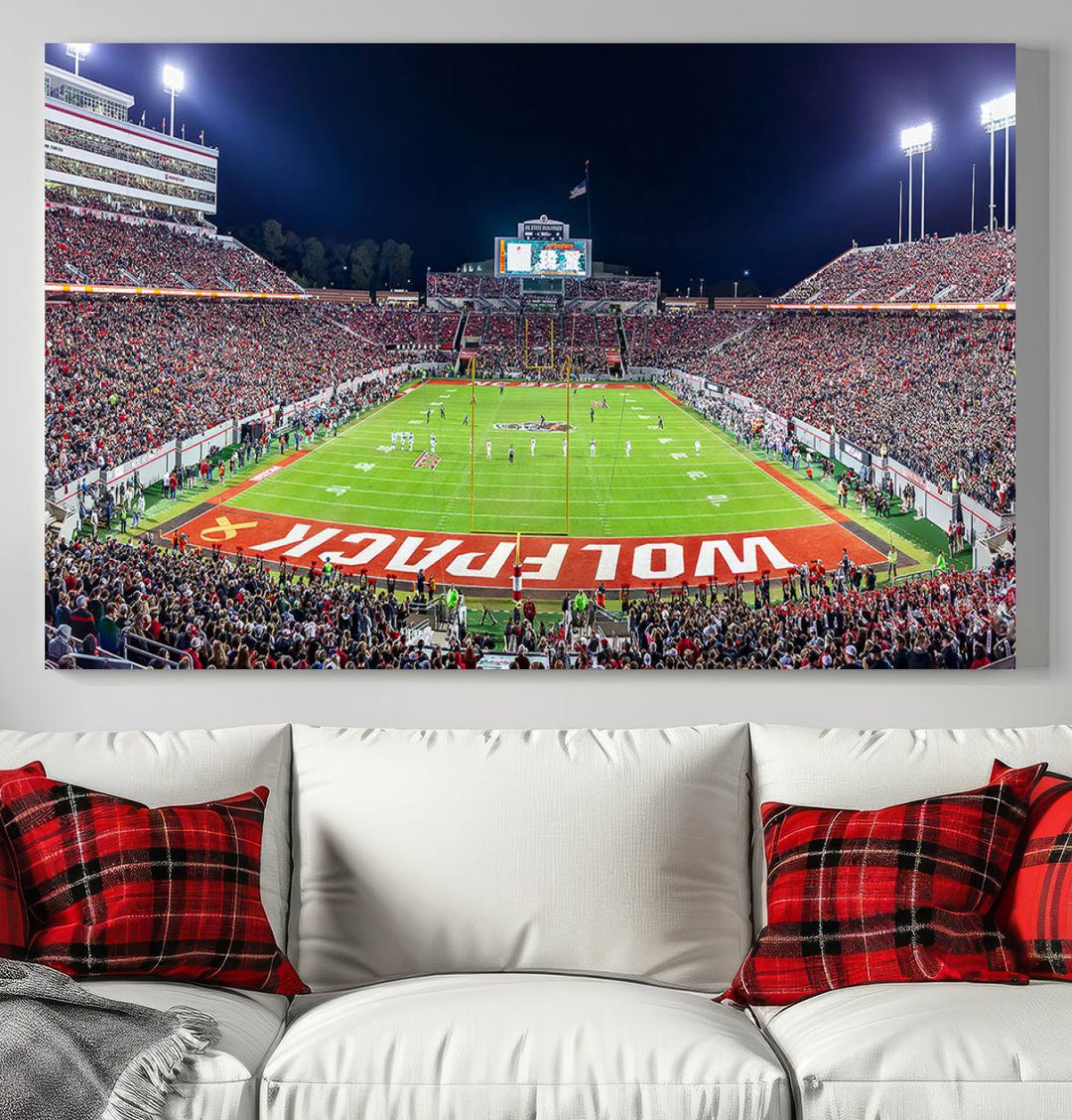 A NC State Wolfpack Football Team print of Carter-Finley Stadium at night features WOLFPACK illuminated brightly in the end zone grass.