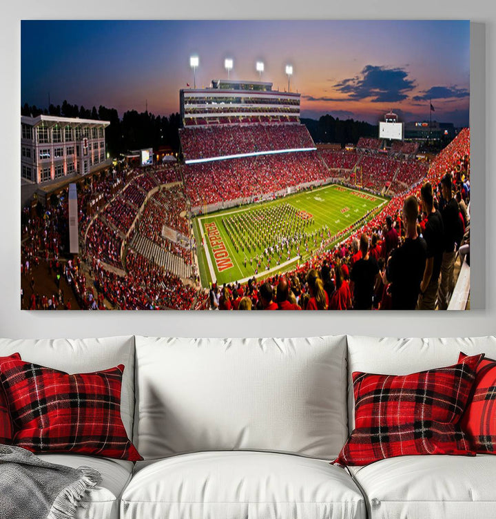 A print of a bustling Carter-Finley Stadium at dusk, featuring fans and a band, captures the essence of NC State Wolfpack football.