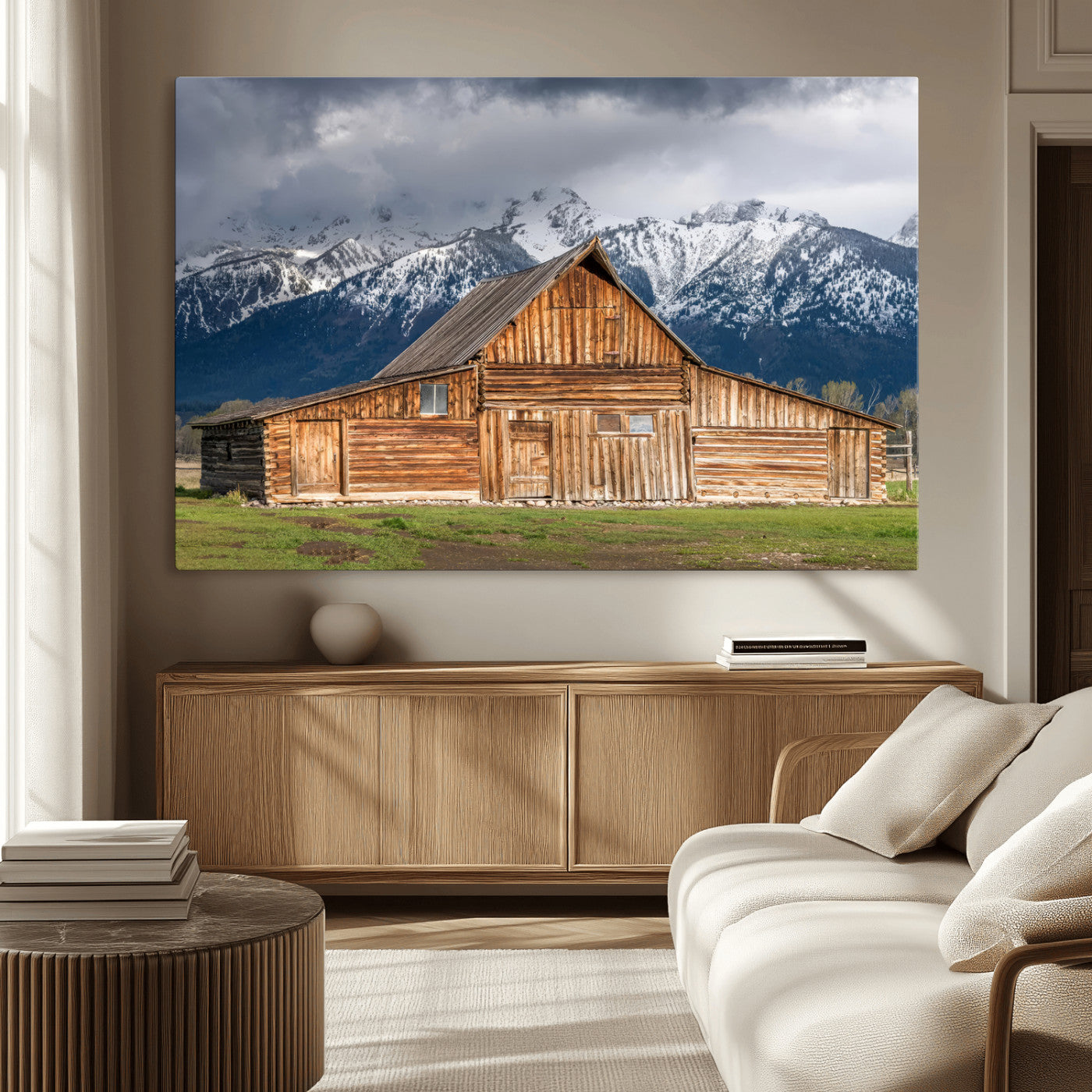 A stunning wall art canvas print featuring a rustic wooden barn set against a backdrop of snow-capped mountains under a dramatic cloudy sky, perfect for adding a touch of rural charm to any space.