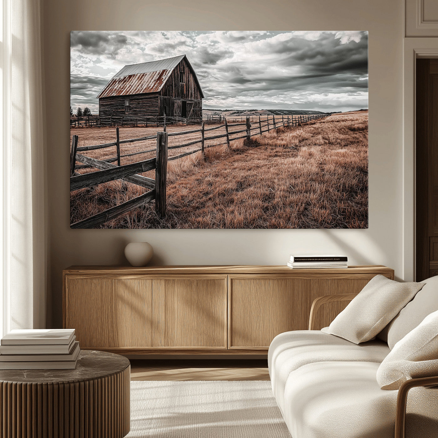 "Black-and-white photograph of a rustic barn with a weathered roof, surrounded by a wooden fence and vast golden fields under a moody sky."