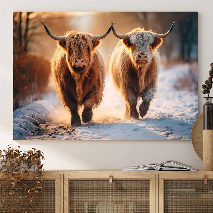 The wall art is a Scottish Highland Cow Horn canvas print featuring cows on a snowy path bathed in warm sunlight, serving as a rustic decor piece.