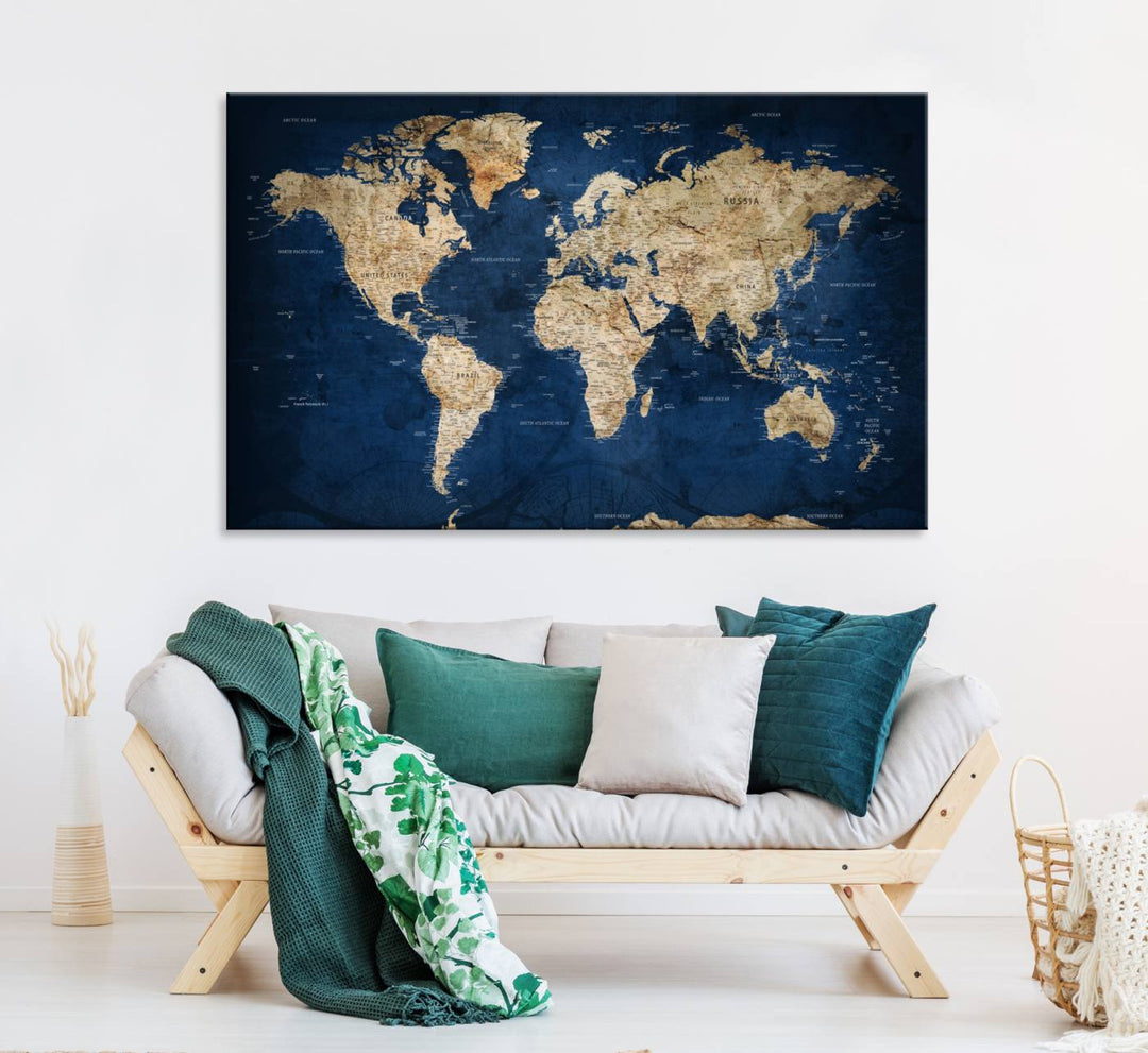 A large framed world map canvas print features beige landmasses set against a grunge-stained deep blue ocean background, creating an intriguing piece of wall art.