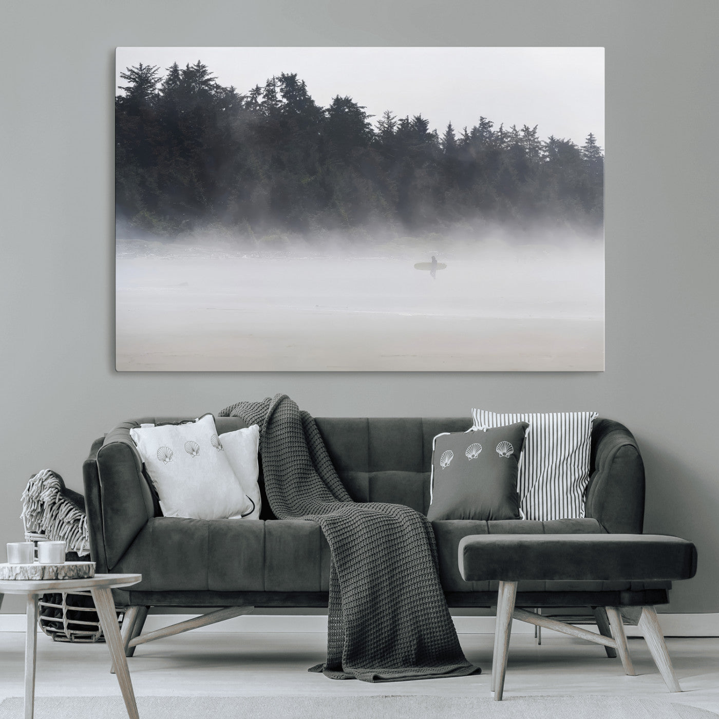 A lone surfer carrying a board through a misty shoreline, surrounded by dense trees and fog, creating a peaceful and mysterious coastal scene.