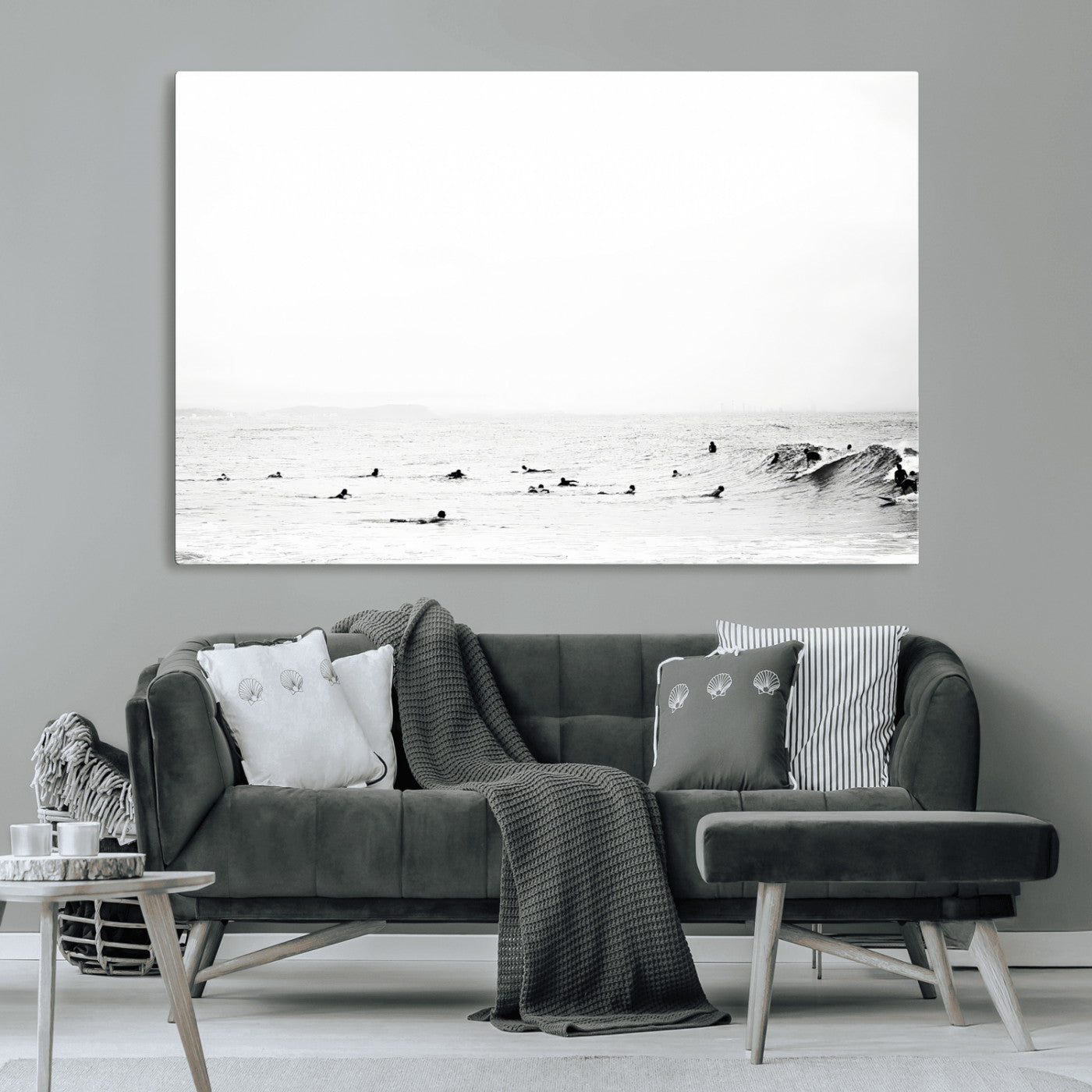 A group of surfers floating in the ocean, waiting for waves under a vast, moody sky, captured in black and white.