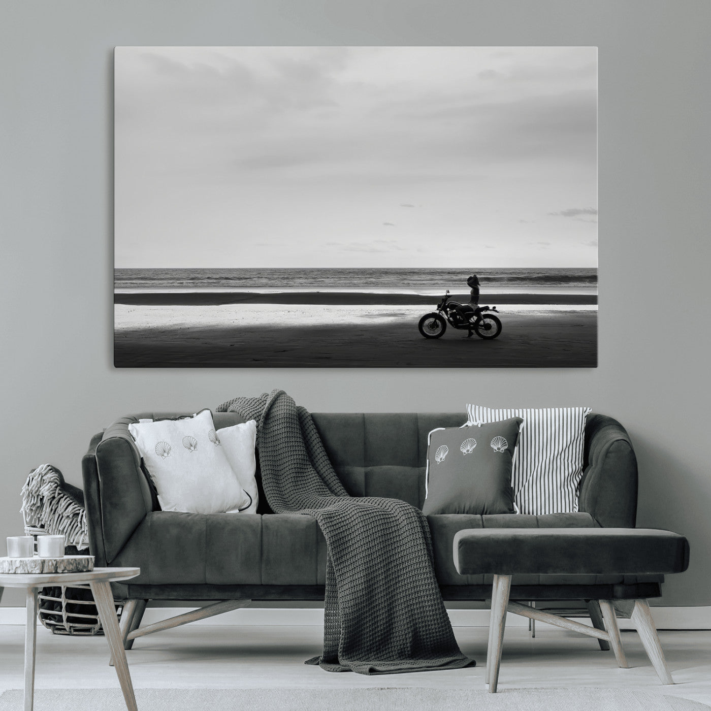 A motorcyclist on a vast beach, gazing at the ocean, capturing a moody and tranquil coastal adventure in black and white.