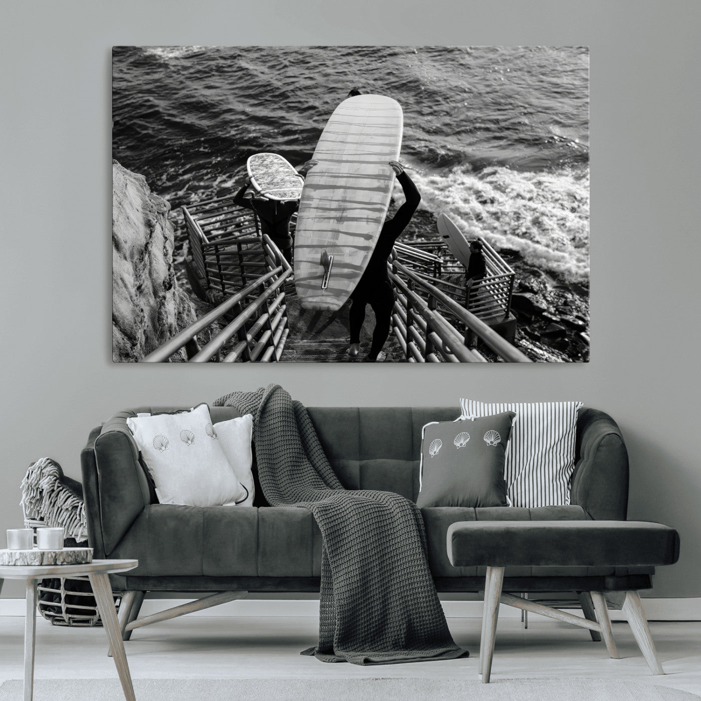 Black and white photo of surfers carrying boards down a rugged cliffside stairway, capturing a bold and adventurous coastal scene.