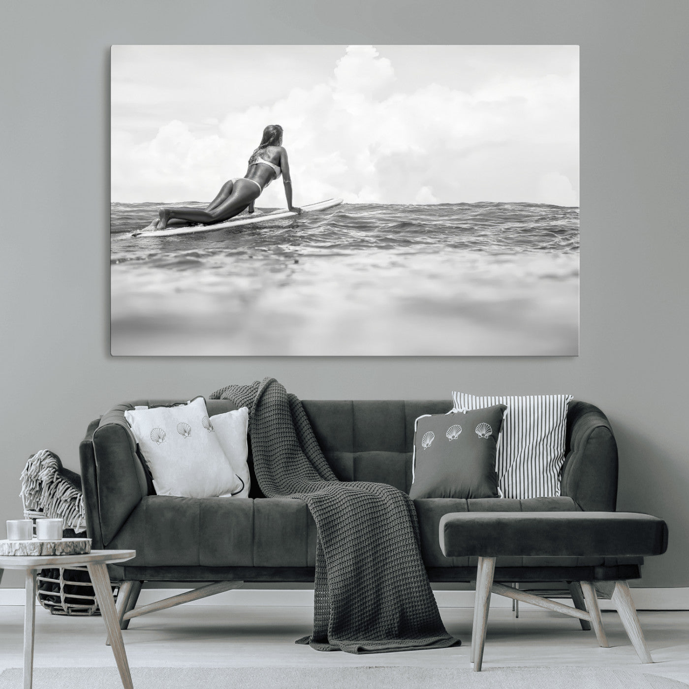 A black and white ocean scene featuring a surfer girl waiting on her board, gazing at the horizon, capturing a tranquil and adventurous coastal moment.