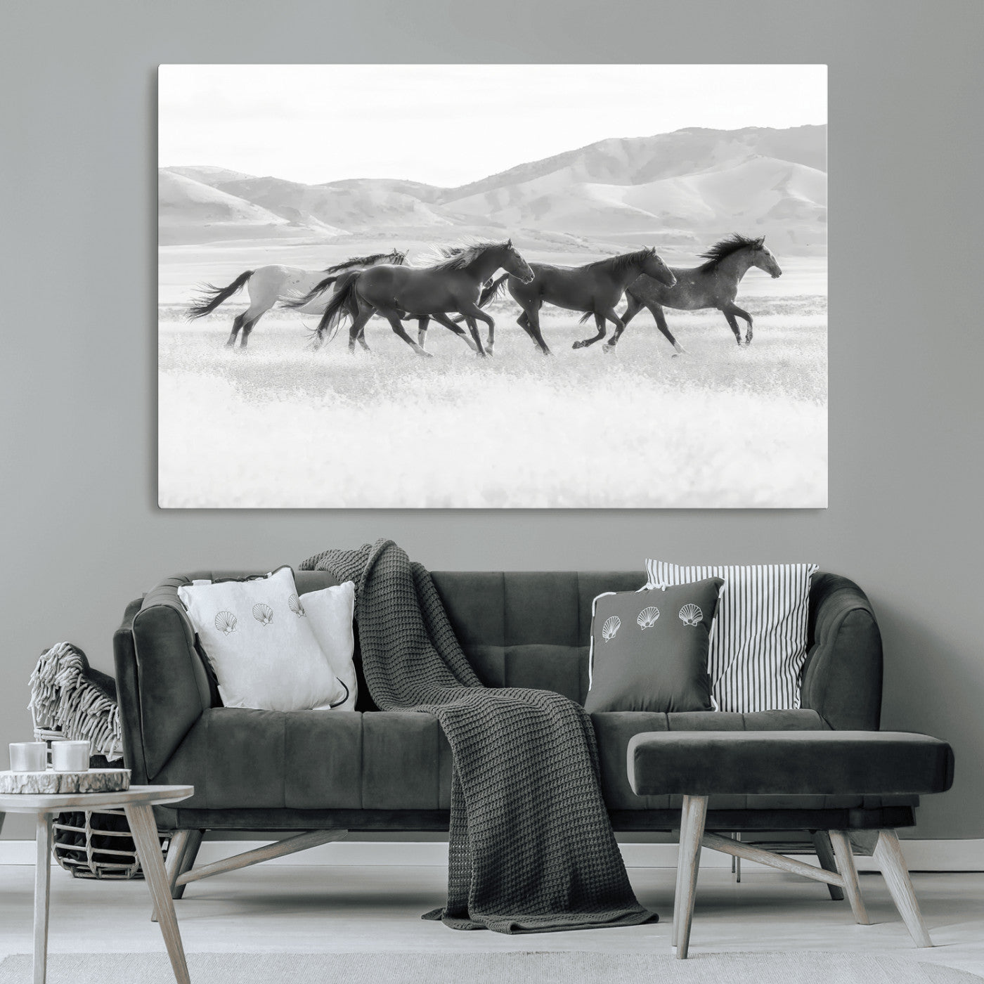 A black and white image of wild horses running freely across an open grassland, capturing the power and beauty of untamed nature in a rustic western setting.