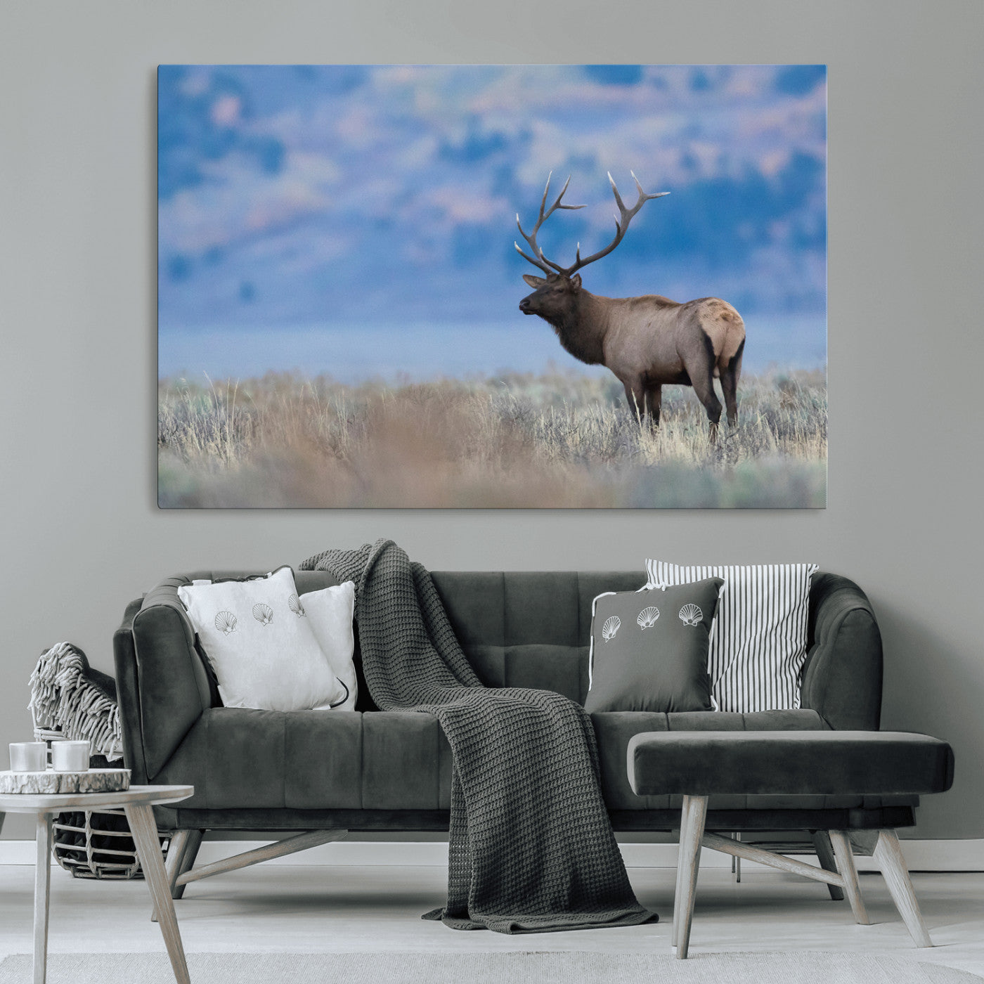 Elk with large antlers standing in open field, mountains blurred in background, perfect for rustic cabin or lodge-style decor.