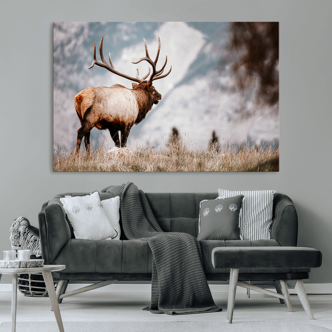 Majestic elk with large antlers standing in grass with snowy mountains in background, perfect for rustic cabin or lodge style decor.
